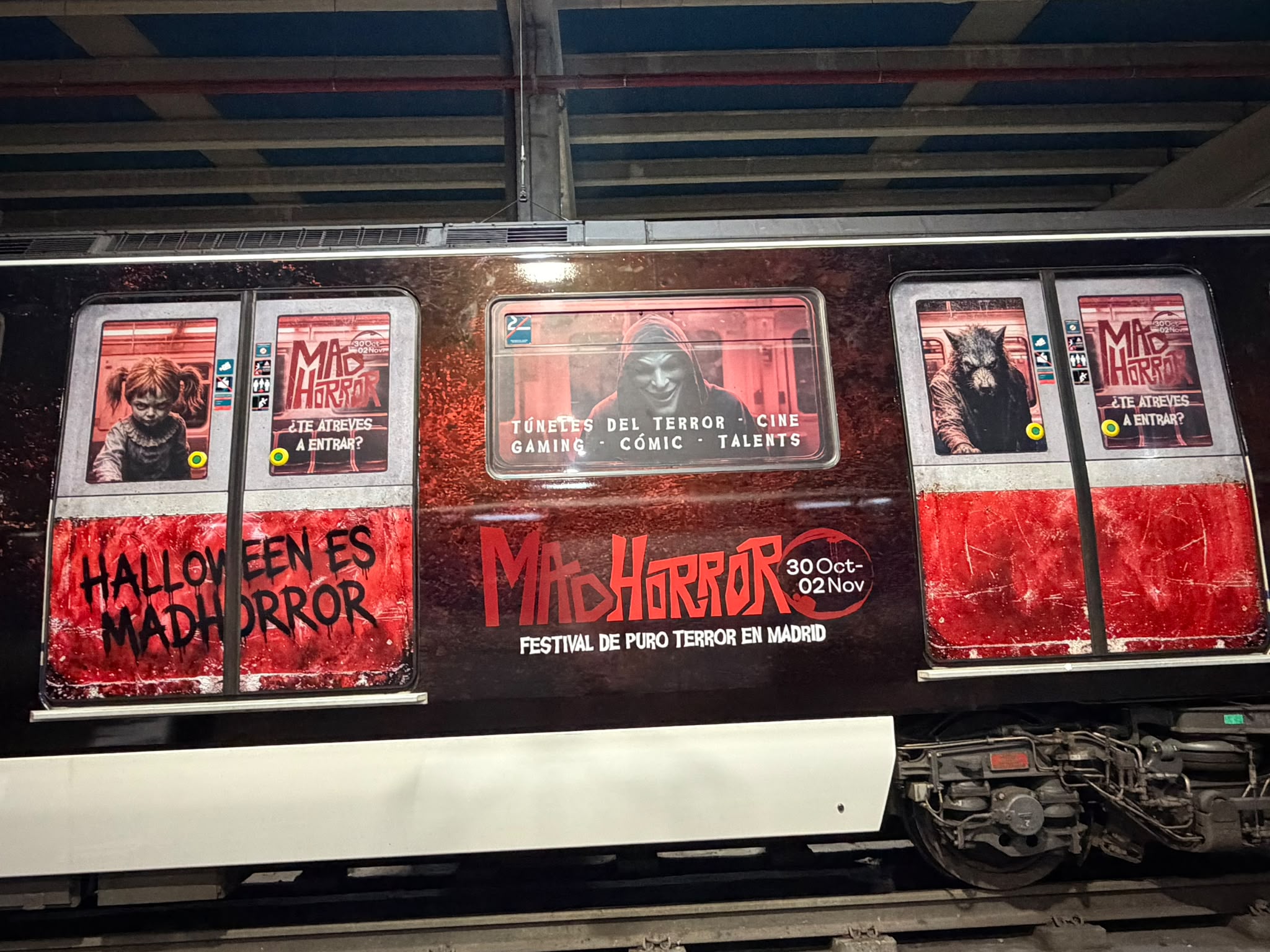Lateral de un tren rotulado con la gráfica roja y negra de la campaña MADHORROR · fotografía 2