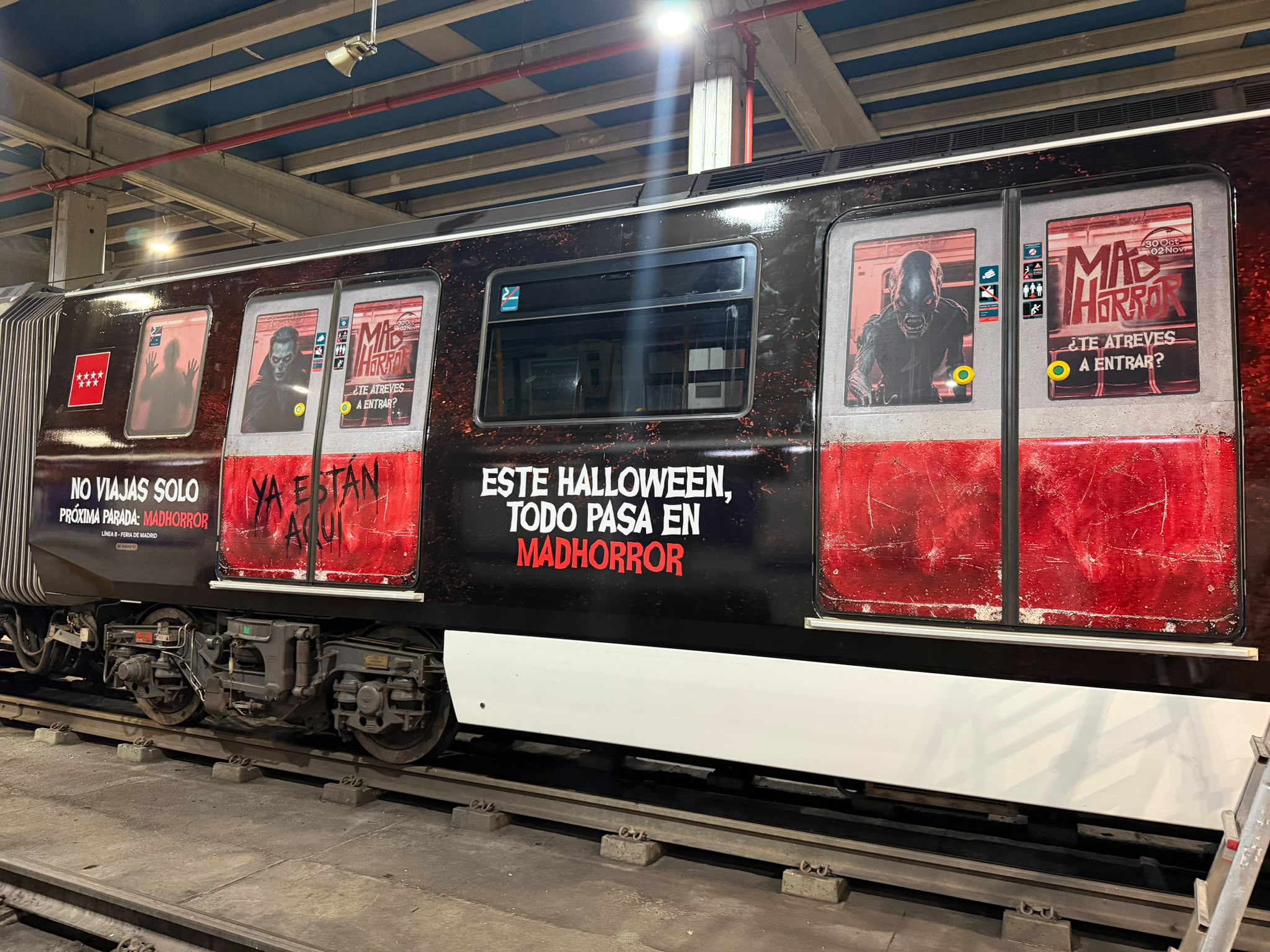 Lateral de un tren rotulado con la gráfica roja y negra de la campaña MADHORROR · fotografía 1