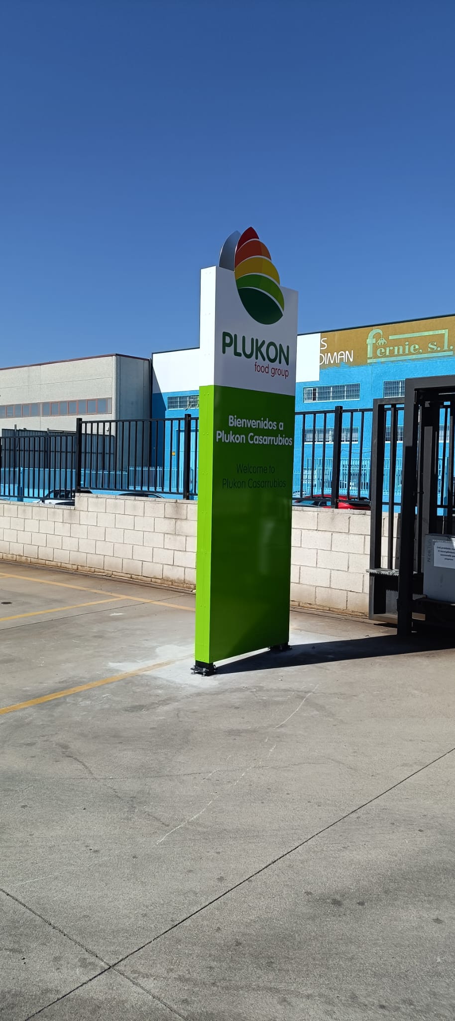 Tótem exterior de Plukon con gráfica corporativa verde y logotipo