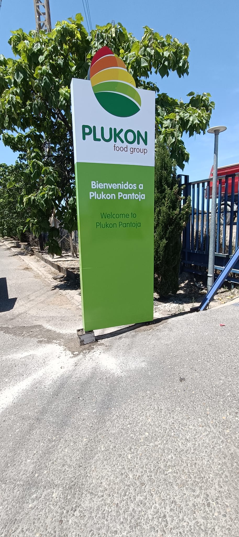 Tótem exterior de Plukon con gráfica corporativa verde y logotipo · fotografía 2