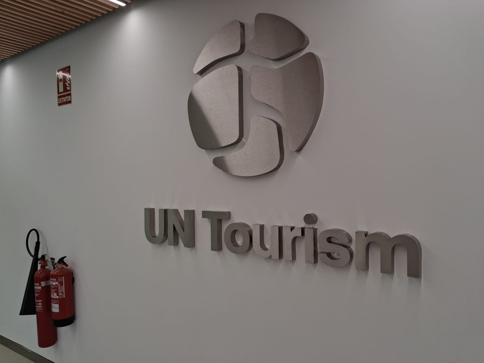 Logotipo y letras corpóreas de UN Tourism instalados en una pared de recepción · fotografía 1