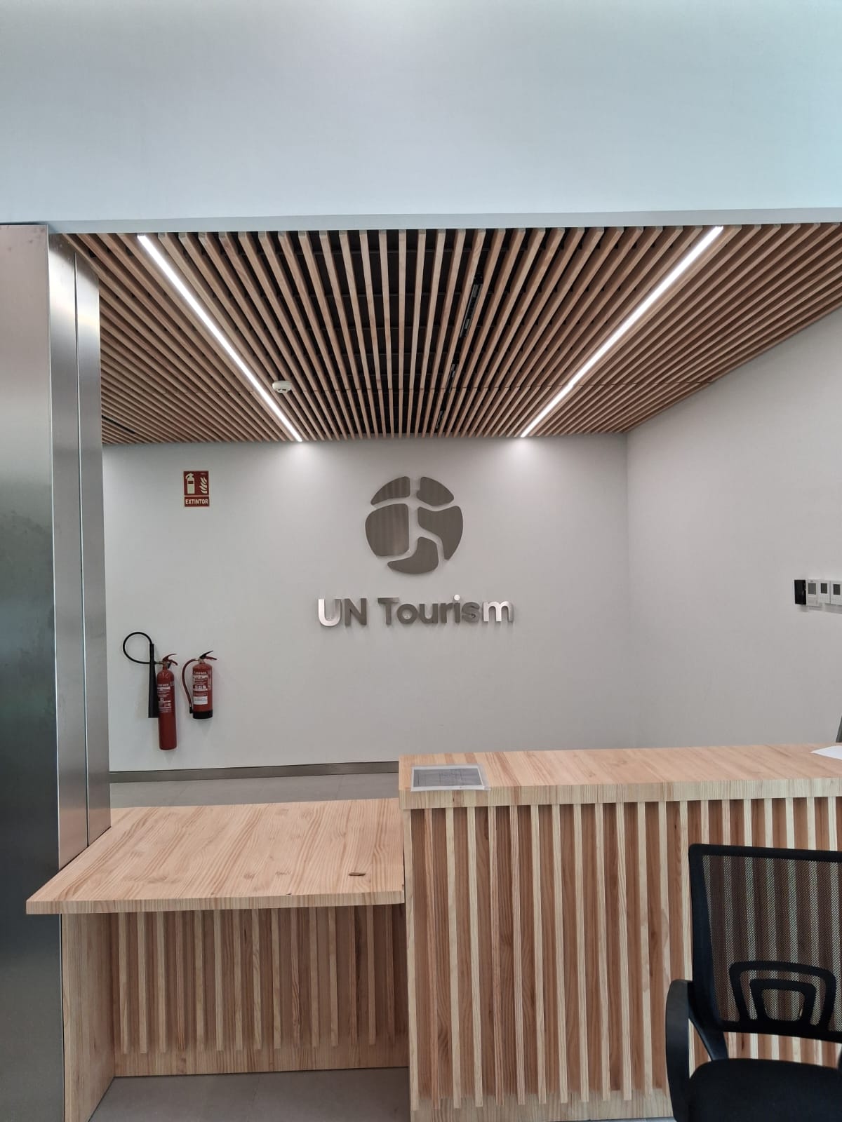 Logotipo y letras corpóreas de UN Tourism instalados en una pared de recepción · fotografía 2